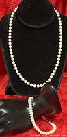 Pearl necklace displayed on bust with bracelet draped on display hand