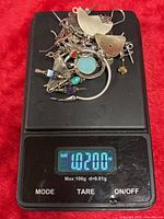 Pile of mixed sterling silver jewelry pieces on digital scale reading 1.02 oz