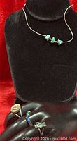 Overall view of necklace on display with three rings on mannequin hand