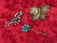 All three brooches on red fabric