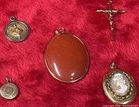 Group shot of five pendants and charms on red background
