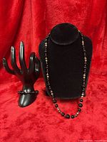 Necklace displayed on bust with bracelet on hand form