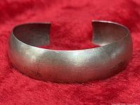 Full view of sterling silver cuff bracelet on red background