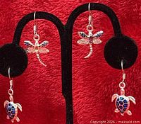 Overview of both turtle and dragonfly earring pairs on stand