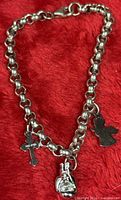 Full view of sterling silver bracelet showing all three charms on red background.