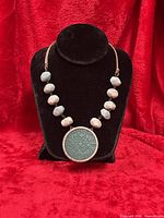 Full view of necklace on bust showing beads, pendant, strap