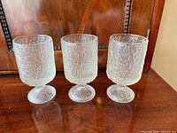 Three clear textured Crystal Ice wine glasses side by side on wooden surface