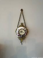 Full view of clock hanging on wall with chain