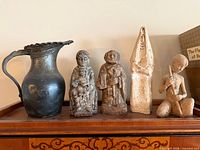 Group shot of metal pitcher and four figurines on shelf