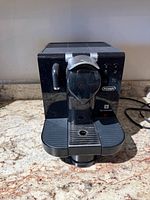 Front view showing lever, capsule slot, drip tray, steam wand