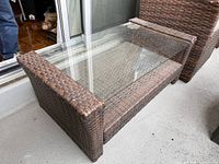 Full view of wicker coffee table with glass top on balcony