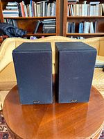 Front view of both black Klipsch B-10 bookshelf speakers on table