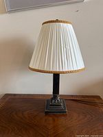 One lamp showing metal column, base, pleated shade with gold trim