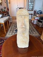 Front view of beige stone Moai sculpture on table