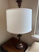 Lamp showing white drum shade on bronze base
