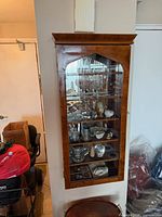 Full view of wall-mounted curio cabinet showing glass door and shelves