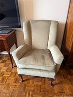 Front view of wingback chair showing upholstery color, seat cushion, and carved cabriole legs