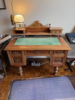 Front view of wood pedestal desk with green felt inlay and upper hutch
