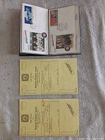 Open binder showing Apollo-Soyuz FDC pages and two yellow APS stamp sales booklets