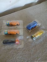 Five sealed miniature cars visible; colours identifiable include blue, orange, yellow, black
