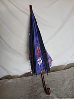 Umbrella closed showing curved wooden handle and canopy material