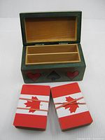 open green wooden card case with interior dividers and two Canadian flag decks beside