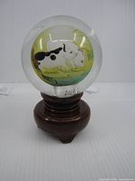 Front view of glass sphere on stand showing pigs painting and signature