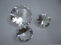 Three faceted clear glass paperweights displayed on flat surface
