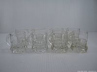 Front view of all eight miniature glass beer mugs