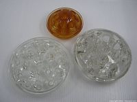Group shot of three round glass flower frogs, two clear, one amber