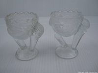 pair of clear glass stork egg cups angled view