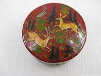 Top view showing painted deer scene on red lacquer lid