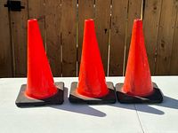 three orange traffic cones side by side on table