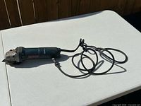 Full view of Bosch angle grinder with cord on table