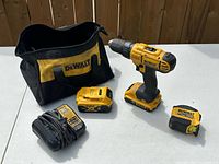 Group view of drill, batteries, charger, tape measure and bag