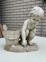 Front view of cast stone child statue with bucket planter