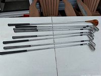 Seven golf clubs laid out showing shafts and grips