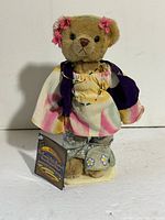 Front view of Ivy bear with clothing, necklace, tag and stand