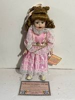 Front view of Vanessa Ricardi porcelain doll standing with certificate card visible