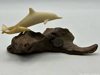 Full view of resin dolphin sculpture on driftwood base