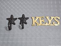 Front view of brass "KEYS" plaque and two cast iron starfish hooks