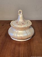 Lidded porcelain trinket box front view showing pearlized finish and lobed body