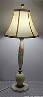 Full view of lamp lit with shade and finial