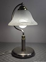 Full view of lit desk lamp showing shade, neck, base, cord