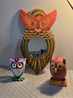 All three owl items together: wooden mirror, ceramic figurine, wicker figurine