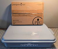 Pampered Chef skewer kit box atop blue casserole with lid