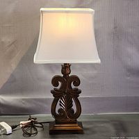 Front view of lamp showing ornate bronze base, cream shade and cord