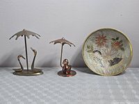 All three items together: brass swans under umbrella, copper duck under umbrella, enamel brass plate
