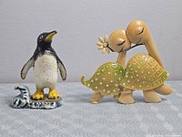 Full view of penguin figurine and kissing turtles earring holder side by side