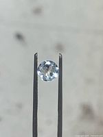 Aquamarine held by tweezers, face-up view